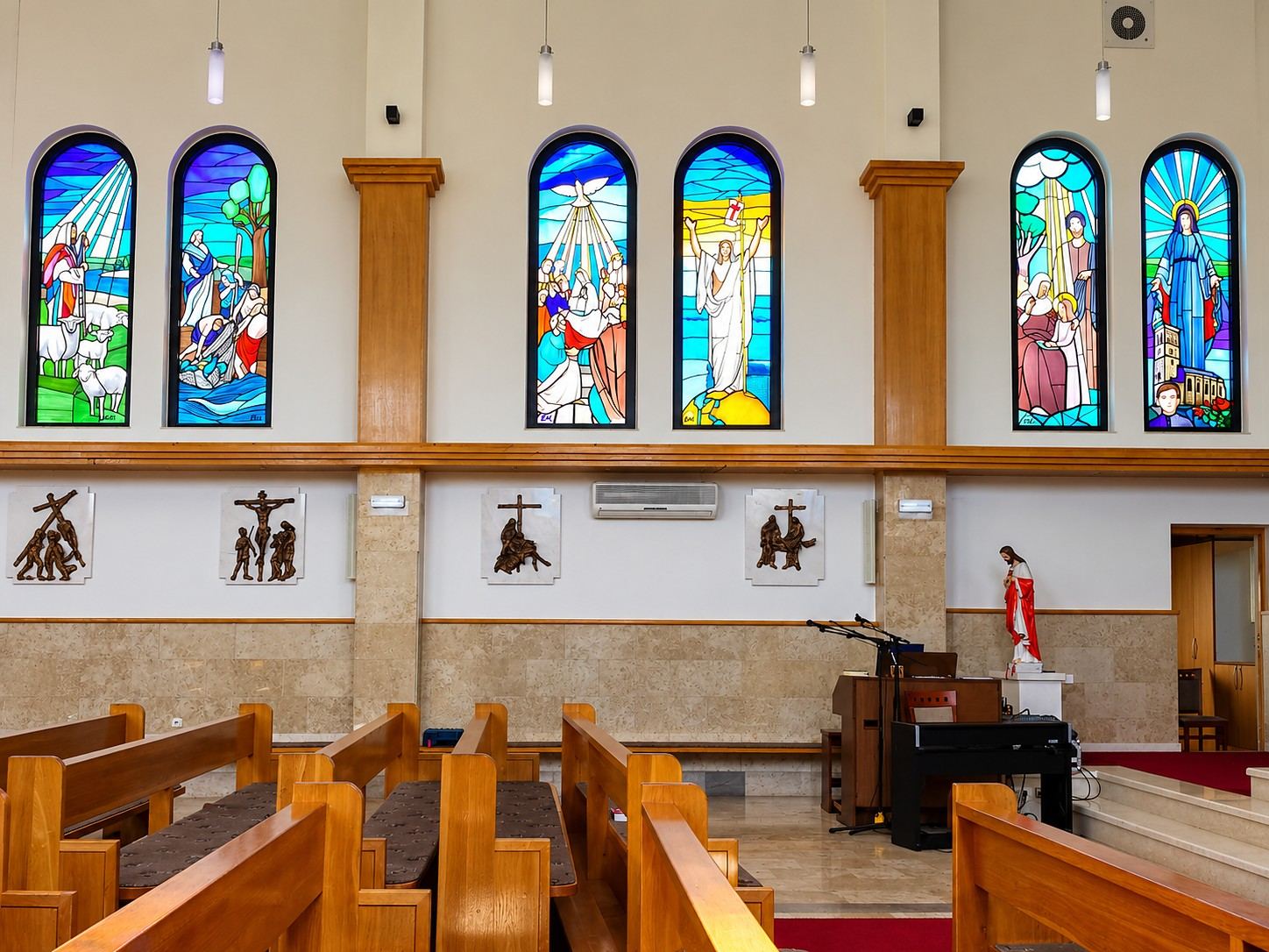The nave of the Church of the Sacred Heart of Jesus in Čeljevo, Bosnia and Herzegovina, with pairs of arched stained glass windows made by Stanisic Studio in Sombor
