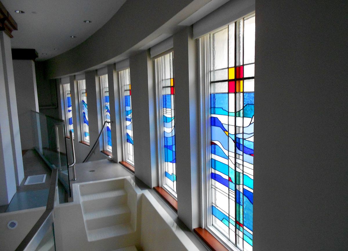 Stained glass windows by Brenda Belfield lining the curved baptistry wall at Heritage Fellowship Church, Reston, Virginia