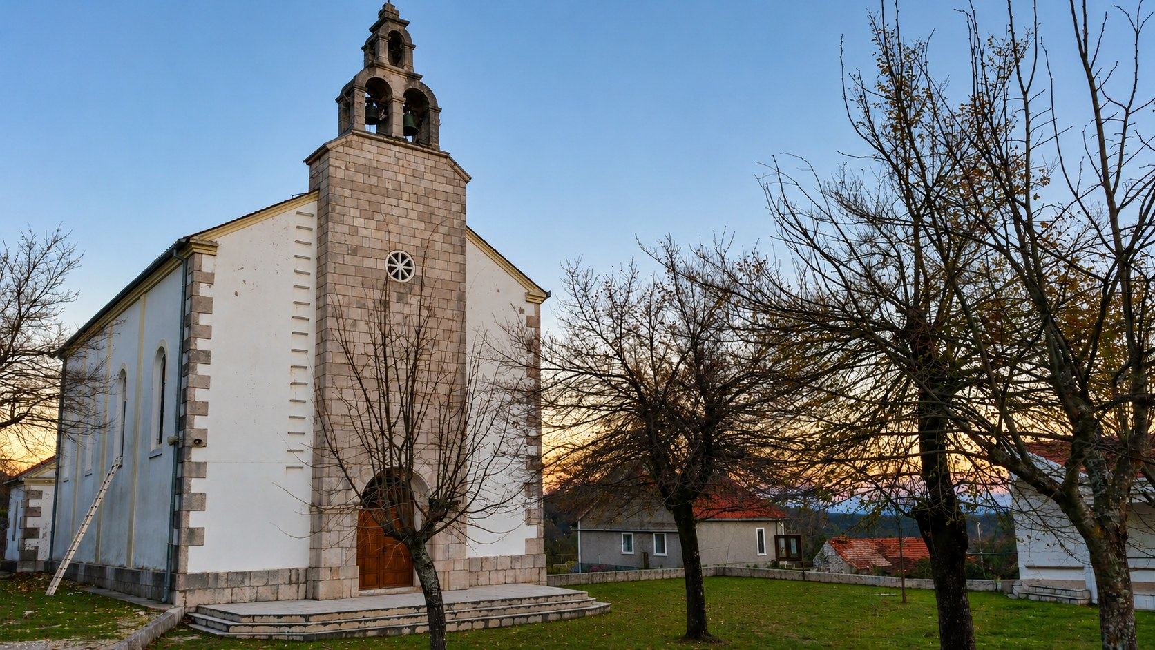 The stone Church of the Immaculate Conception in Hrasno, Herzegovina, at golden dusk, where Stanisic Studio installed 10 stained glass windows of saints in 2013