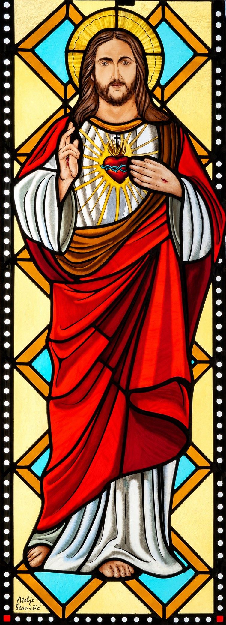 Stained glass window of the Sacred Heart of Jesus in Hrasno, in a white robe and red mantle, blessing