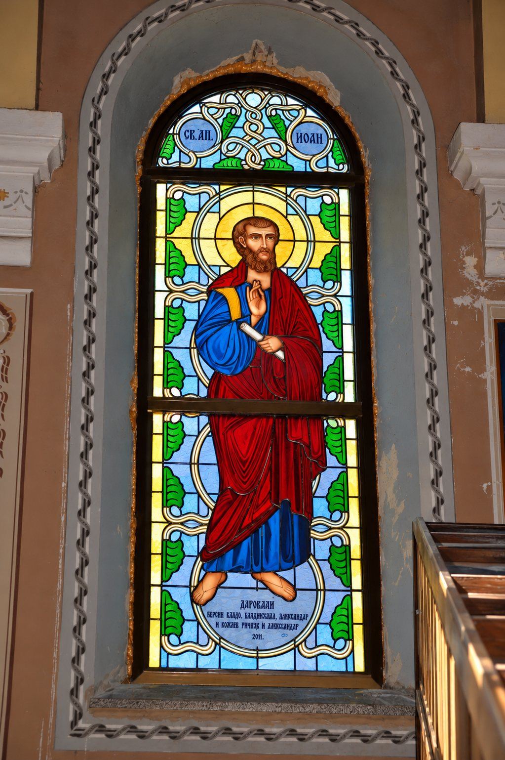 Stained glass window of Saint John the Evangelist in a red mantle, Greek Catholic church in Mikluševci