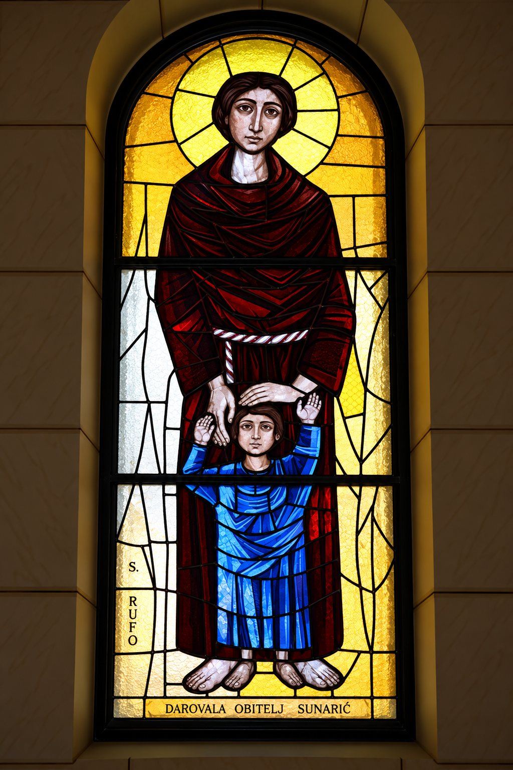 Stained glass window of a saint in a dark red robe with a child in blue, Saint Joseph, Sarajevo