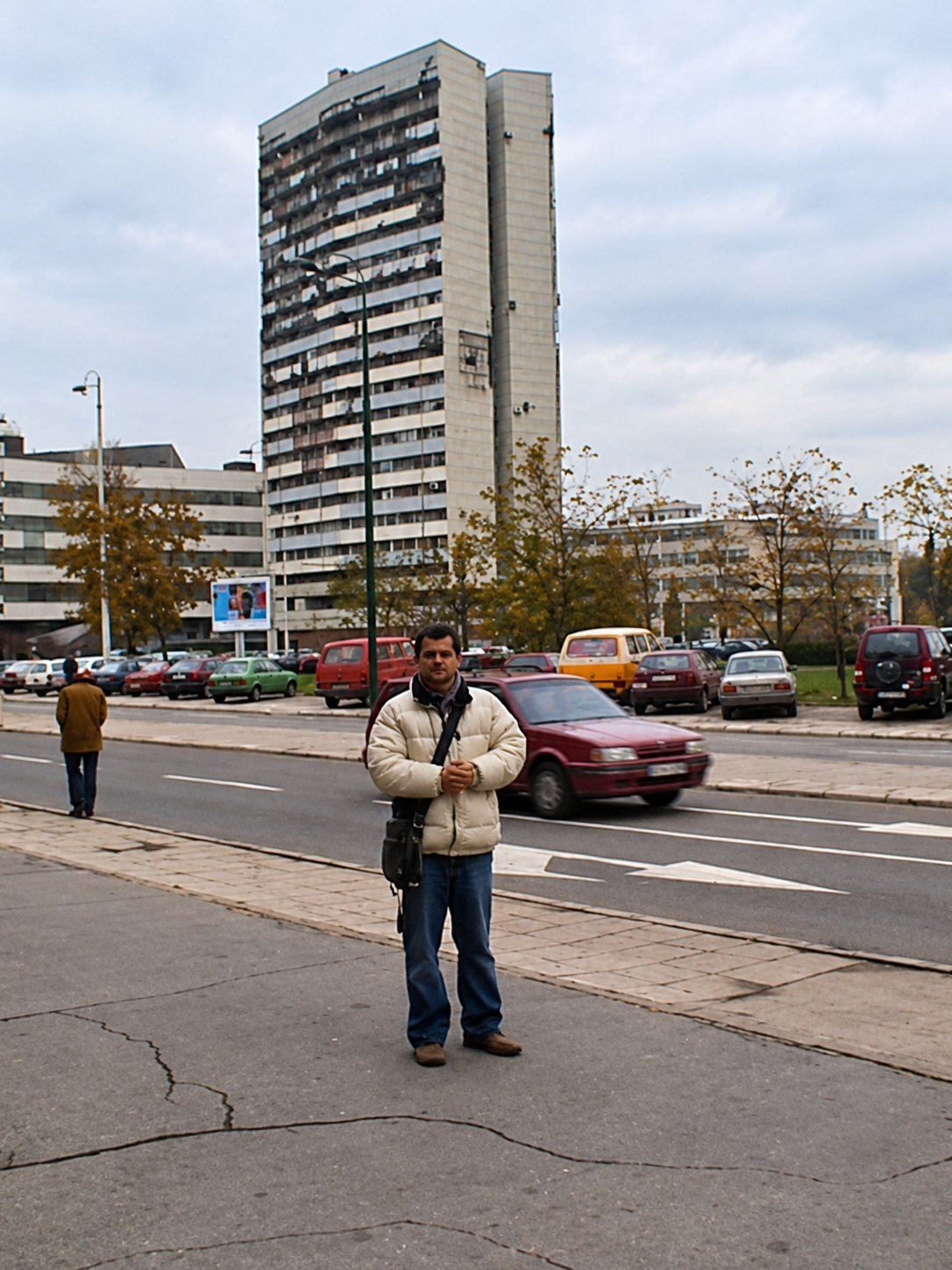 Stevan Stanisic on a street in Sarajevo in 2001, with a war damaged high rise behind him
