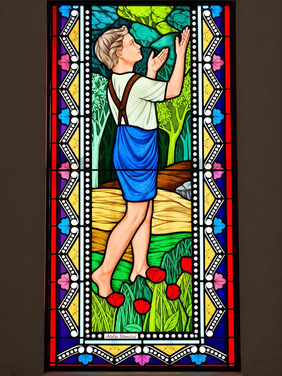 Stained glass window of a barefoot boy reaching up among poppies, Pastoral Centre in Tuzi