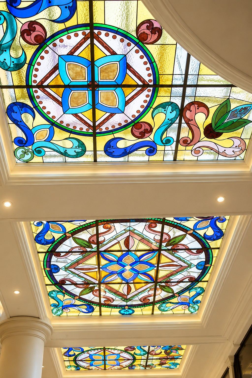 A row of stained glass ceiling lights along a columned corridor at Volzhsky Utyos, Samara Region