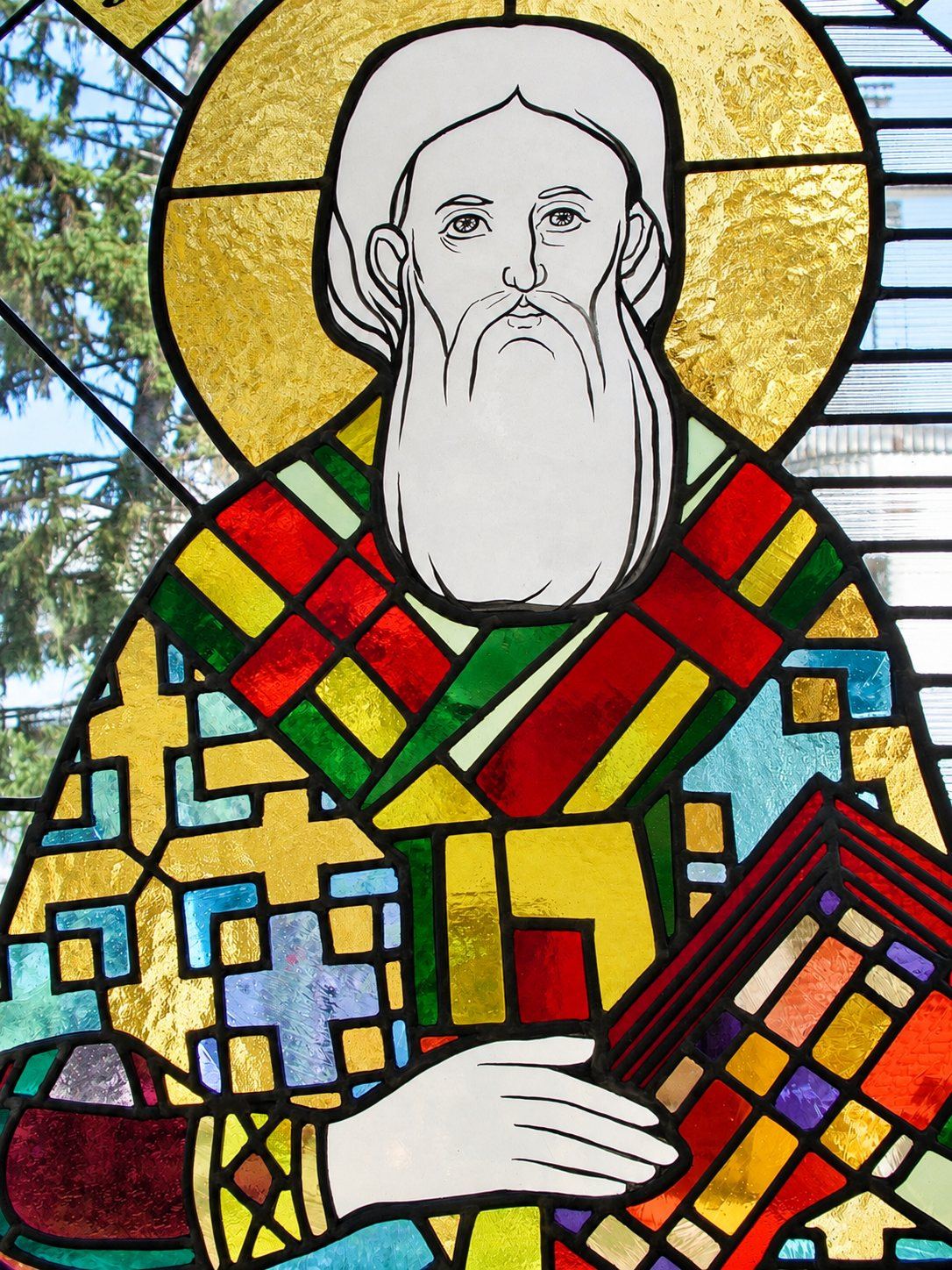 Detail of the stained glass window of Saint Sava with his white beard, golden halo and patterned vestments, Church of Saint Sava, Golija, Montenegro, by Stanisic Studio