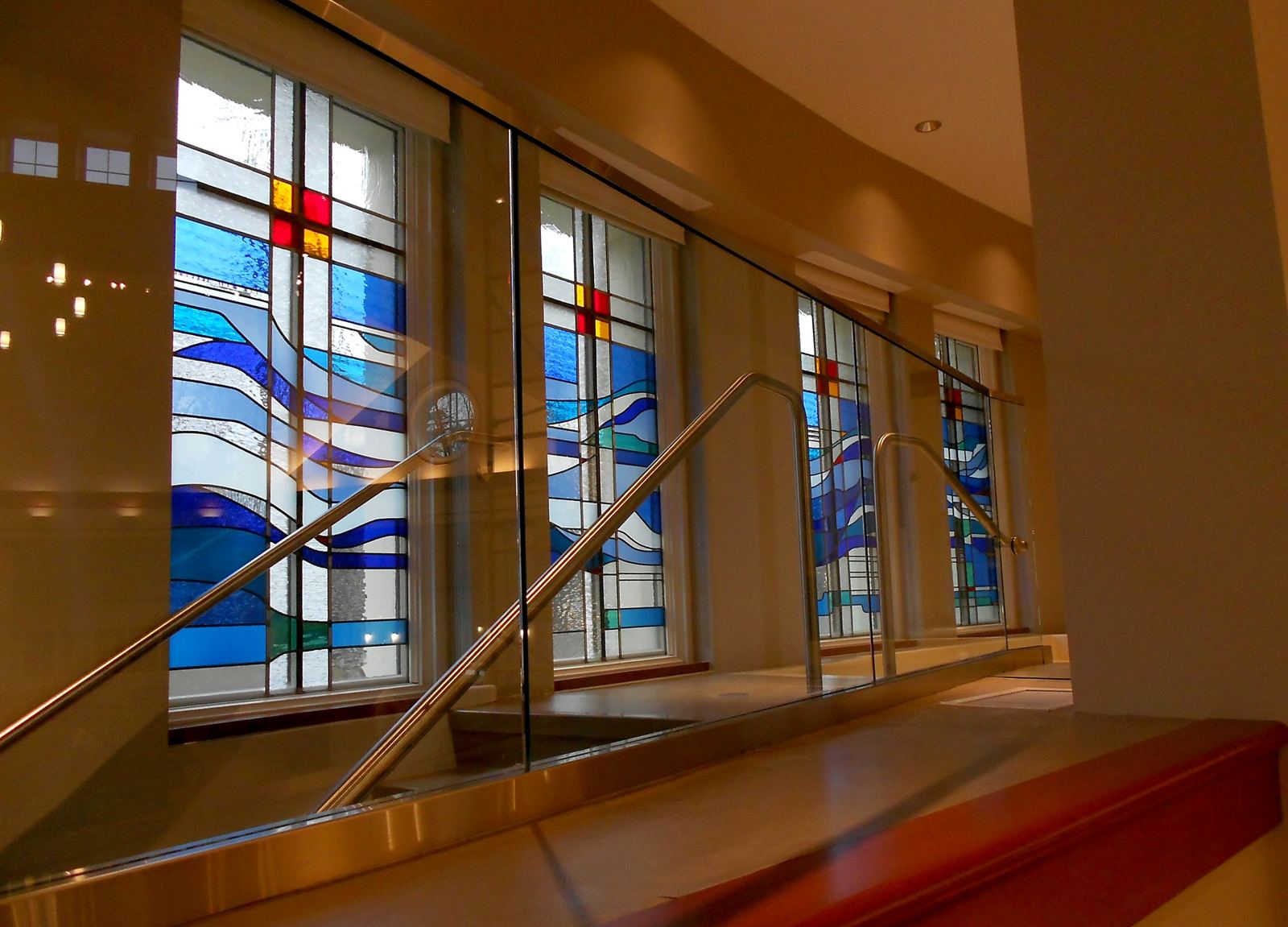 Baptistry stained glass windows at Heritage Fellowship Church, Reston, Virginia, seen through the glass railing in evening light