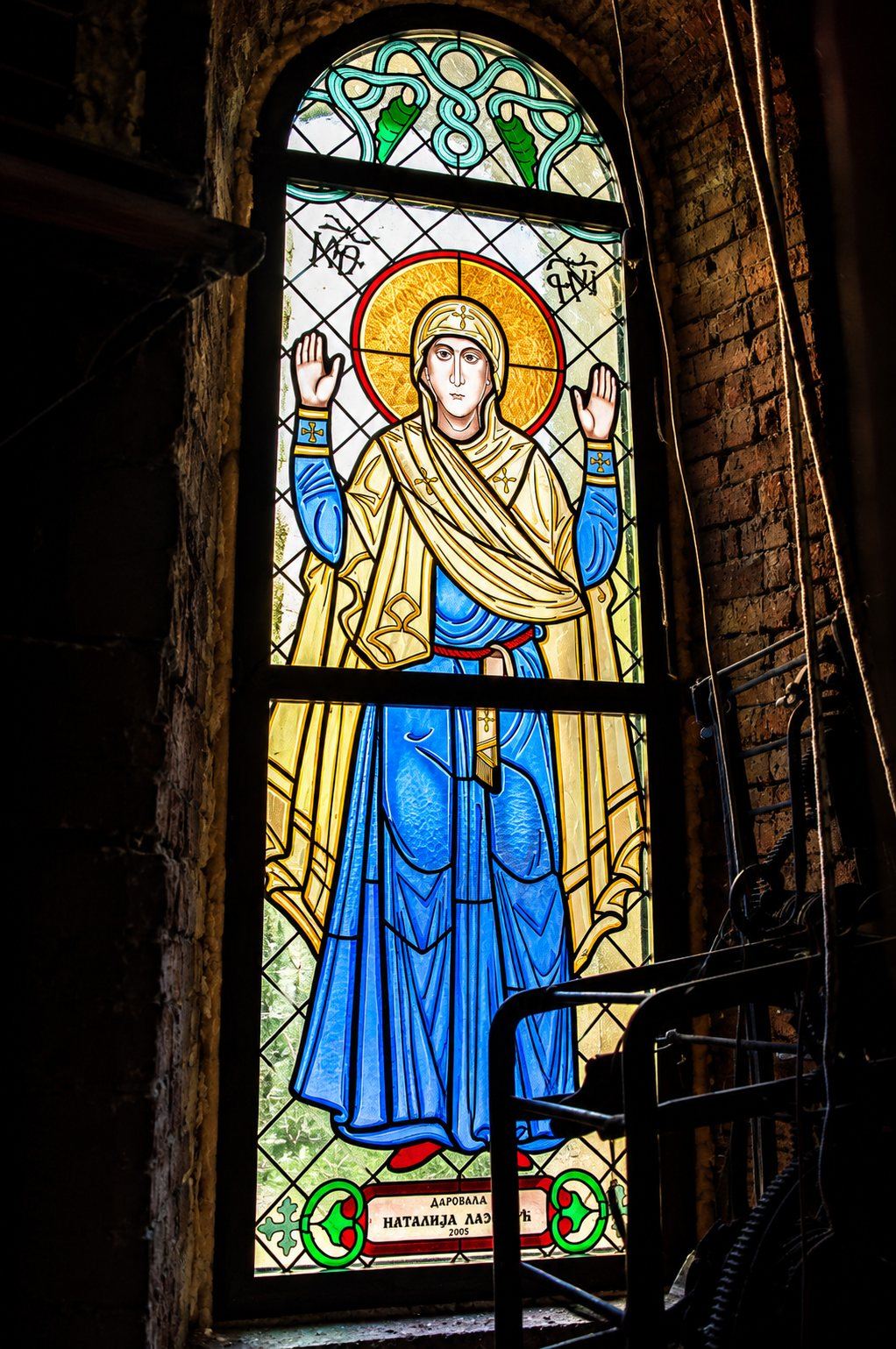Stained glass window of a female saint in prayer with raised hands, Greek Catholic church in Mikluševci