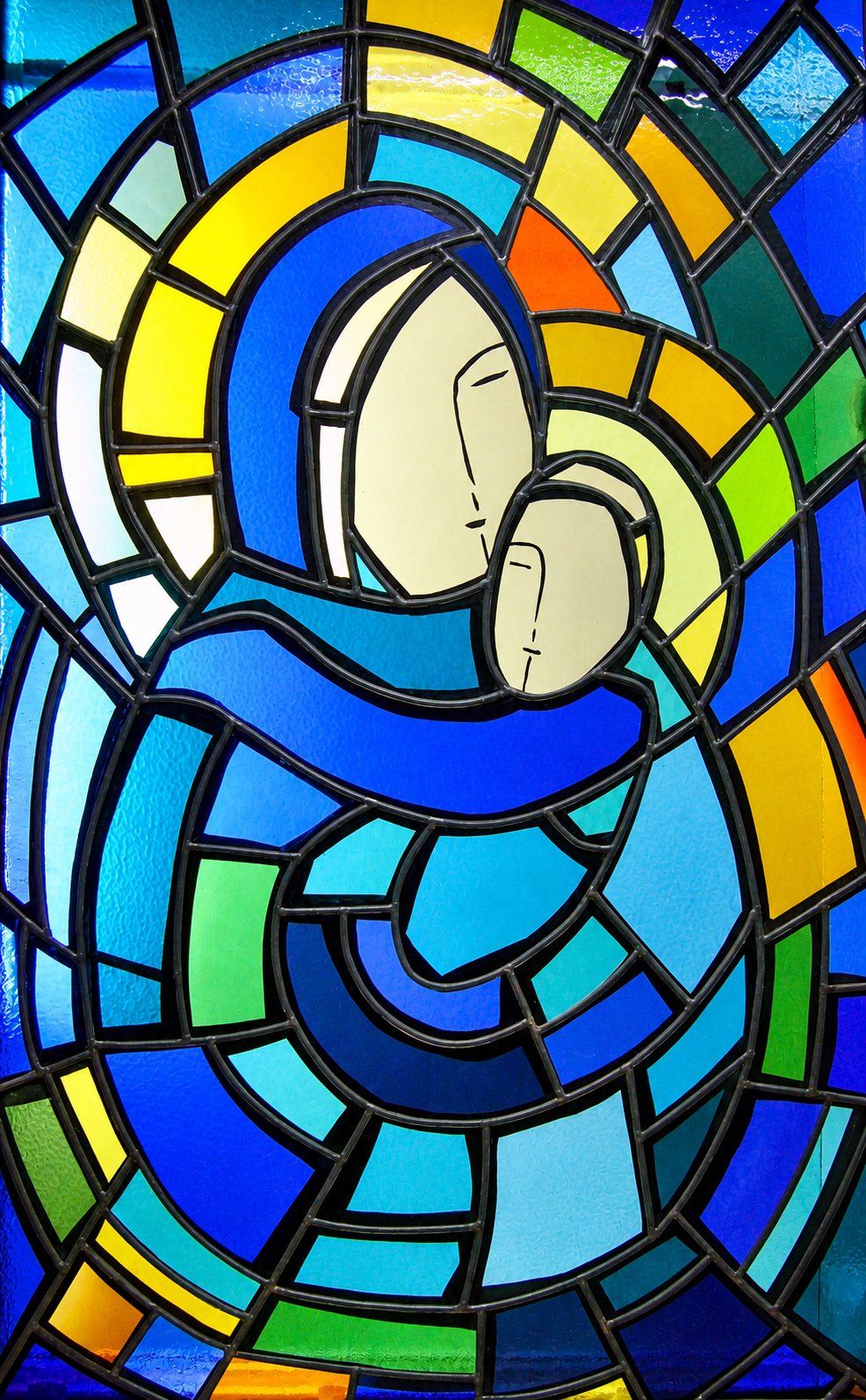 Modern stained glass window of the Madonna and Child in shades of blue, gold and green, City Chapel in Petrovac, Montenegro, by Stanisic Studio